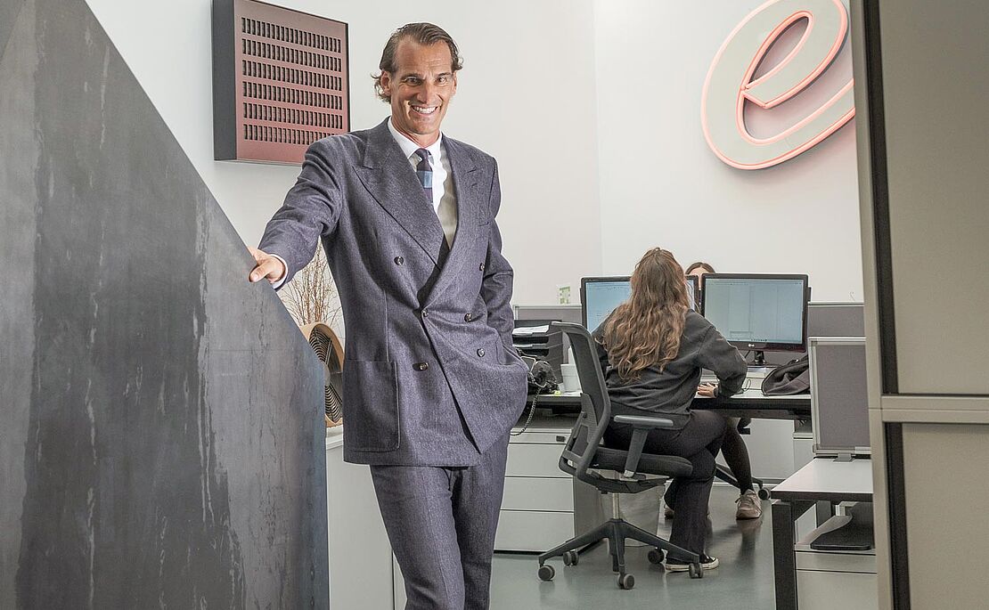 Thomas Schwabl im Anzug lächelnd an die Wand gestützt