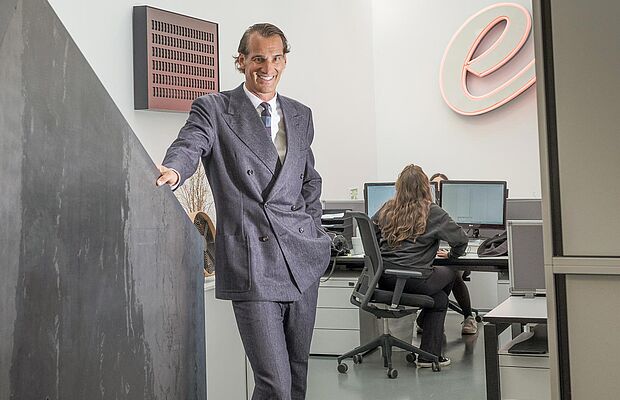 Thomas Schwabl im Anzug lächelnd an die Wand gestützt