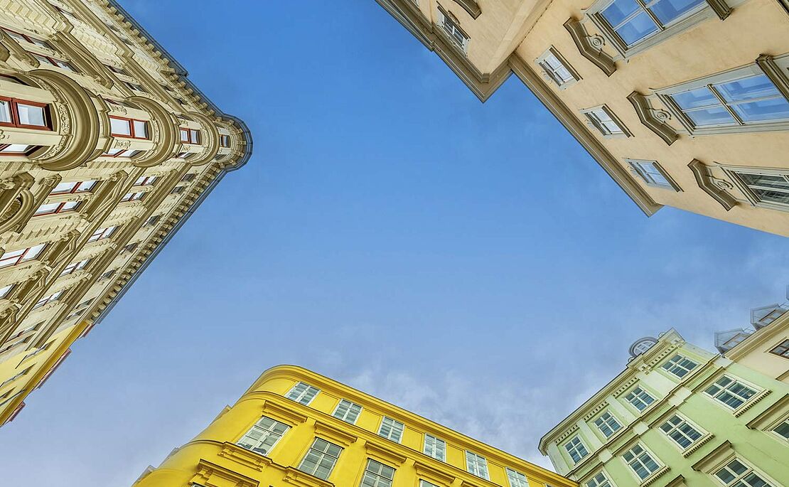 Ein Blick vom Boden aus in den Himmel durch die Häuserschlucht