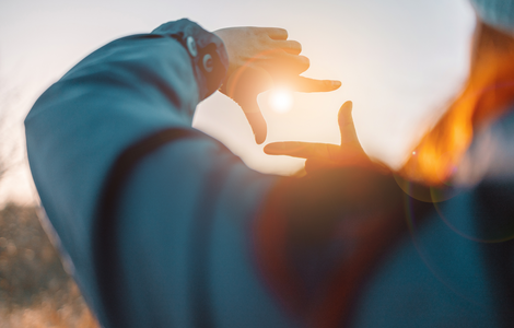 Sonne blitzt durch die Finger einer Frau