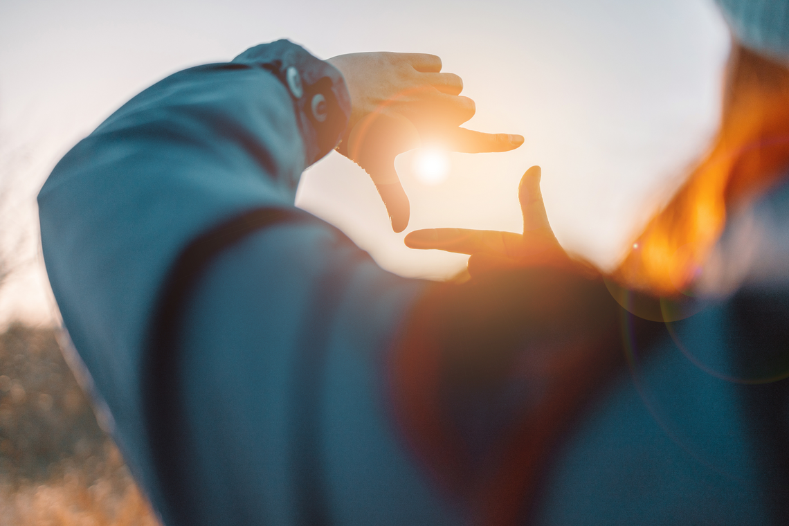 Sonne blitzt durch die Finger einer Frau