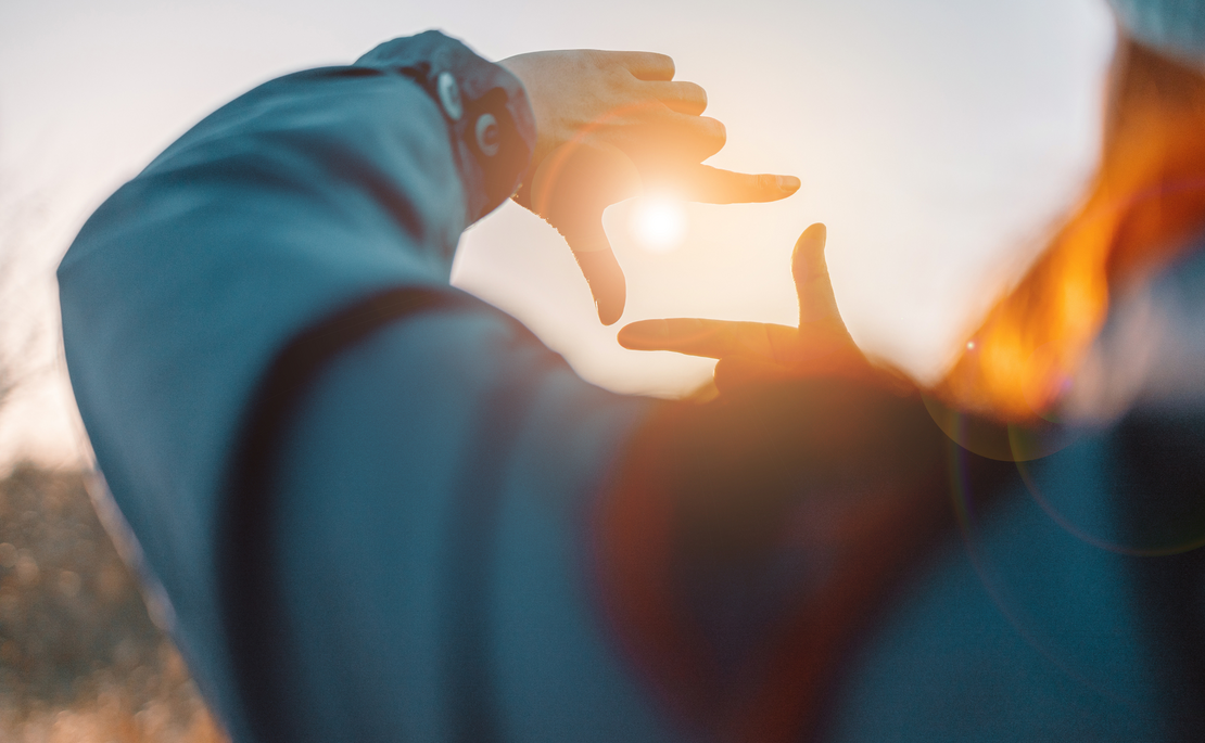 Sonne blitzt durch die Finger einer Frau