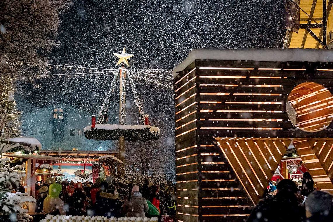 Beleuchteter Adventmarkt Altenmarkt bei Schnee, großer Adventkranz mit goldenem Stern