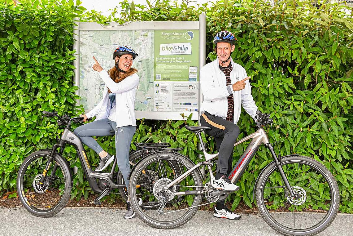 Mann und Frau mit Bikes vor der Karte vom Bike-Netz bike&hike Stegersbach
