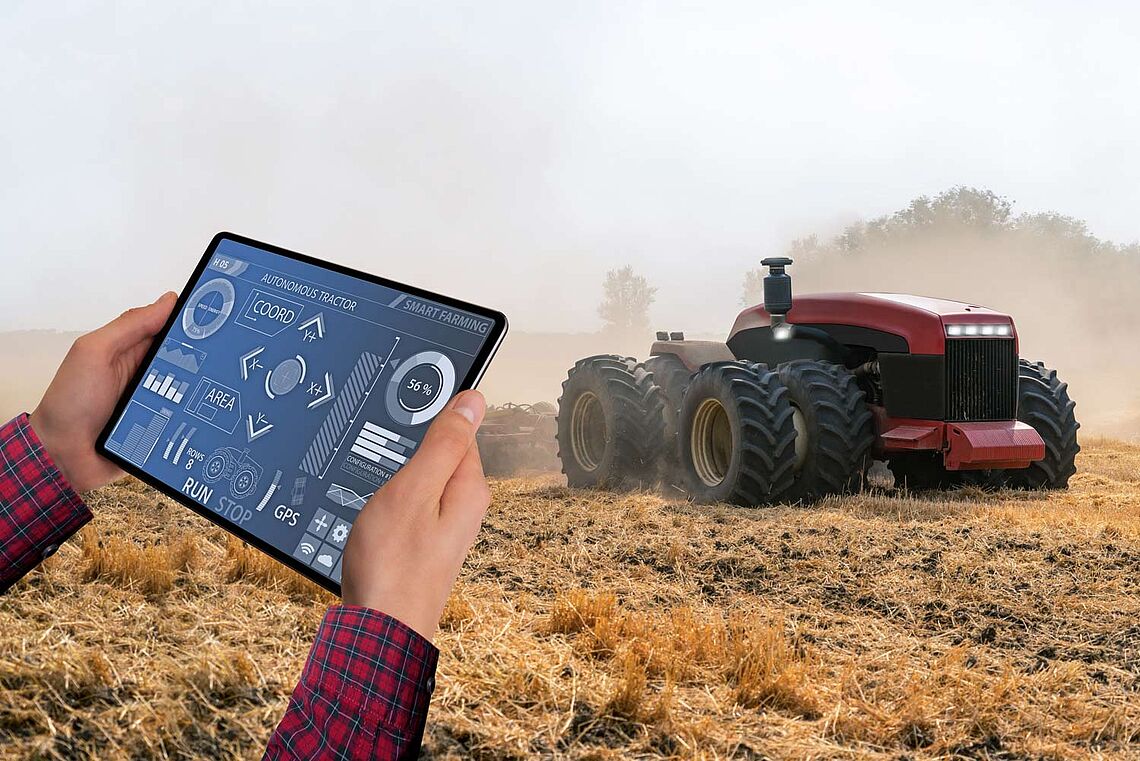 Bauer, der mit einem Tablett einen autonomen Traktor kontrolliert