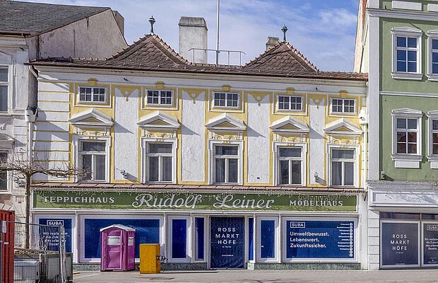 Das Stammhaus in weiß-gelb gehalten, 2-stöckig, mit grüner Firmenleiste "Teppichhaus Rudolf Leiner Möbelhaus"