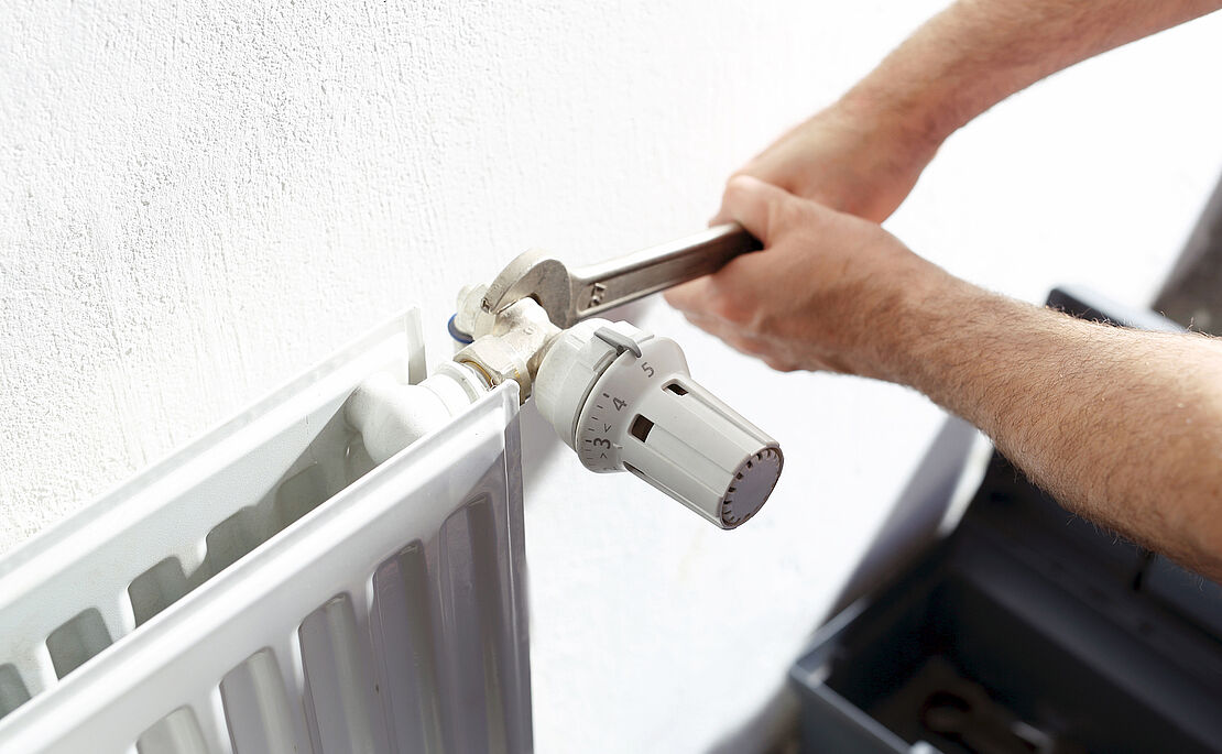 Jemand schraubt an einem Heizkörper