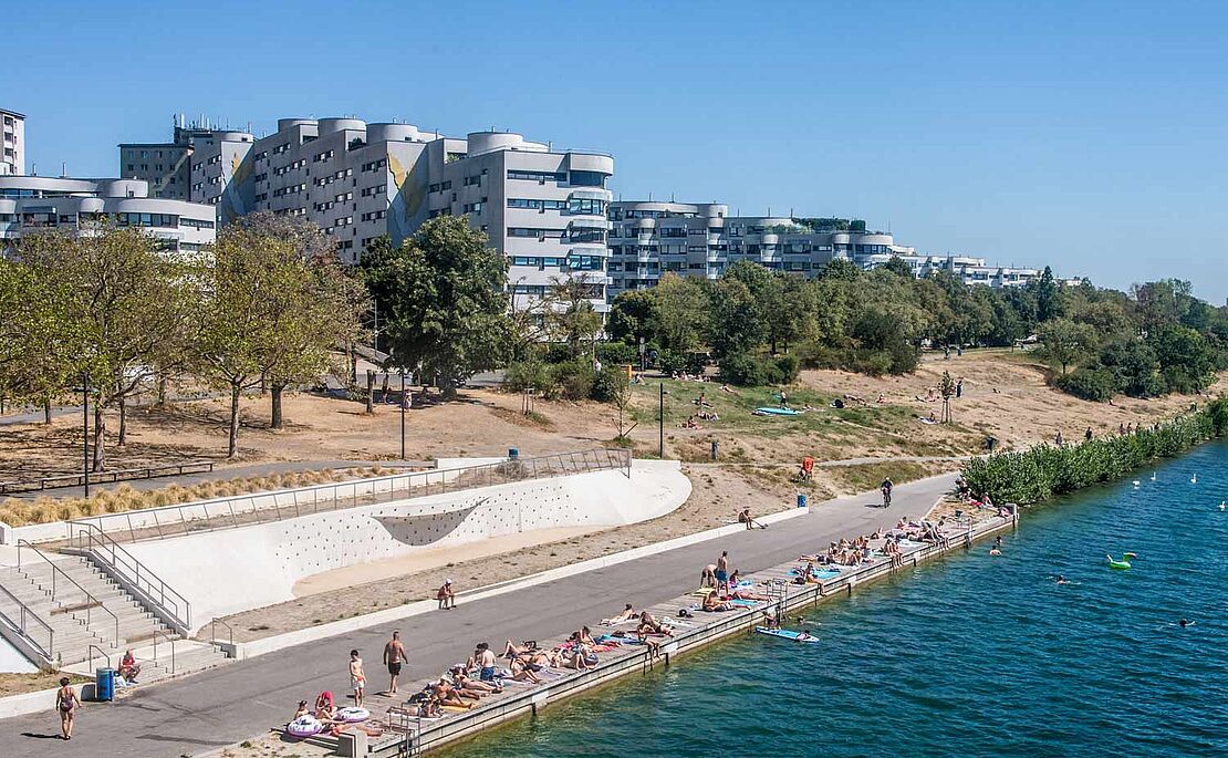 Blick von der Reichsbrücke auf einen kleinen Teil der Neuen Donau im Vordergrund und einem Wohnbau im Hintergrund