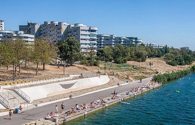 Blick von der Reichsbrücke auf einen kleinen Teil der Neuen Donau im Vordergrund und einem Wohnbau im Hintergrund