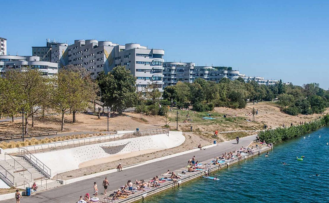Blick von der Reichsbrücke auf einen kleinen Teil der Neuen Donau im Vordergrund und einem Wohnbau im Hintergrund