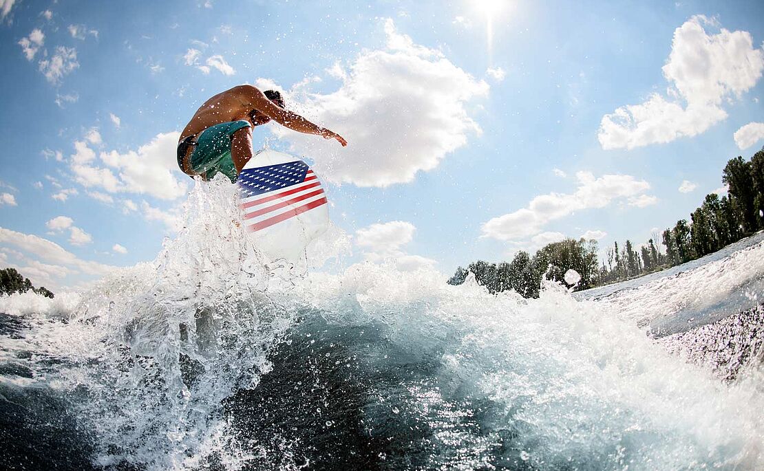 Wellenreiter auf einem Surfbrett mit USA Flagge