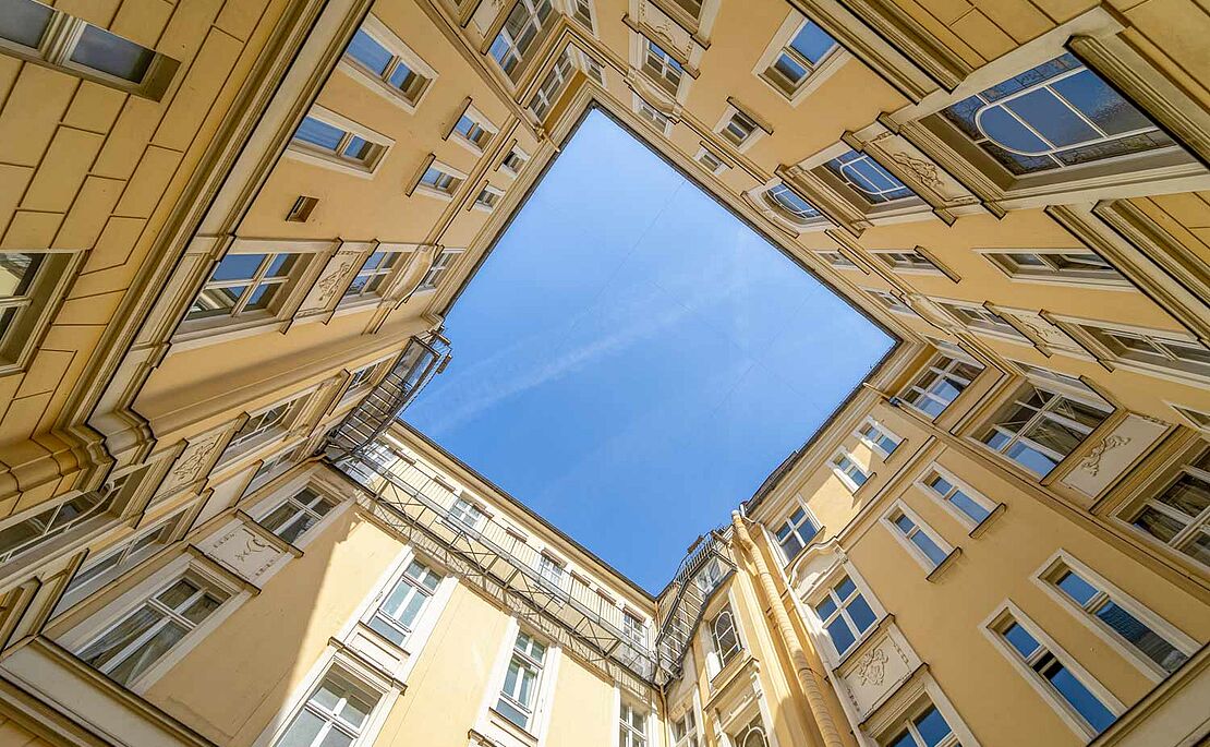 Blick aus einem Innenhof hinauf in den blauem Himmel