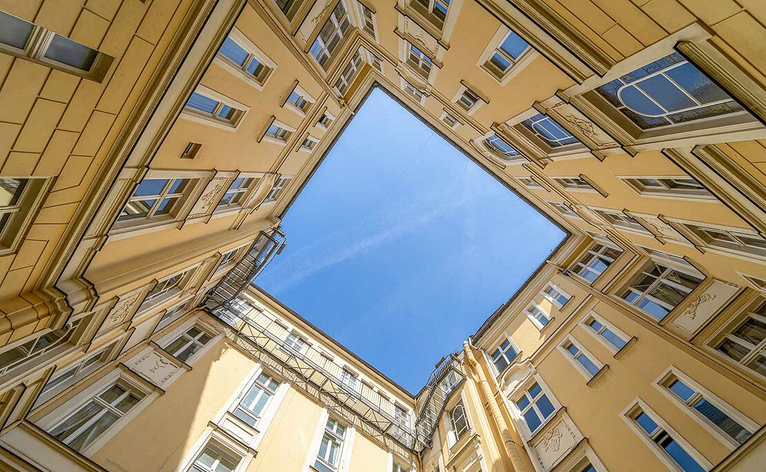 Blick aus einem Innenhof hinauf in den blauem Himmel