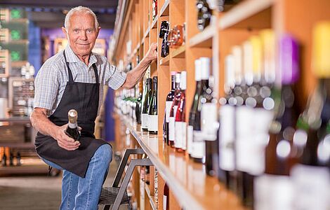 Mann auf Leiter am Weinregal
