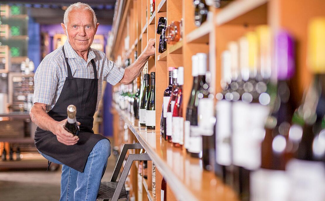 Mann auf Leiter am Weinregal