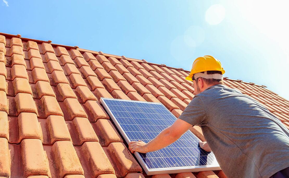 Arbeiter, der ein Photovoltaik-Element am Dach montiert