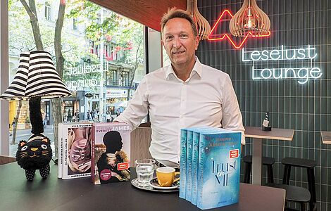 Klaus Magele in der Leselust Lounge mit Büchern und Kaffe vor ihm