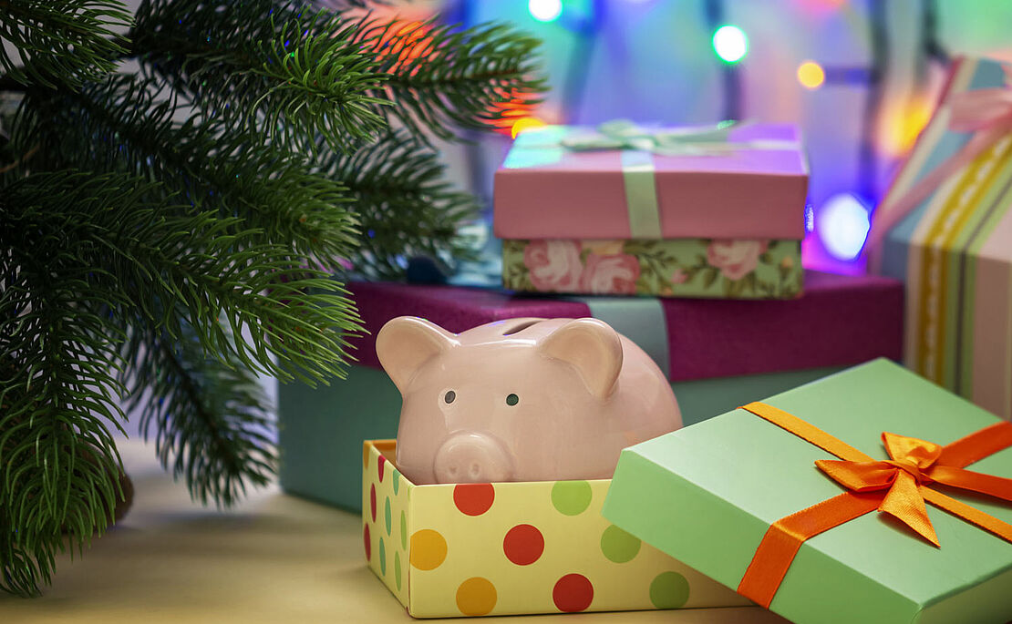 Sparschwein in einer Geschenkschachtel neben Tannenzweig