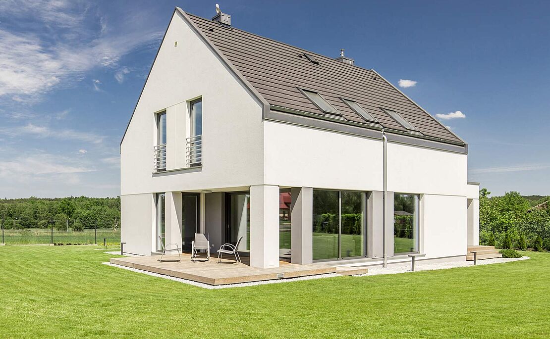 Neu erbautes Einfamilienhaus, blauer Himmel, grüne Wiese rundherum