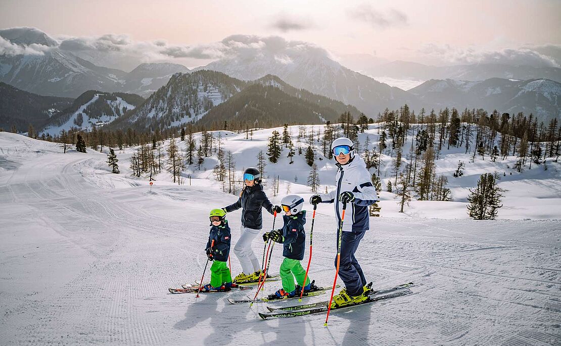 Eine Familie mit zwei Kindern auf Skiern auf Skipiste