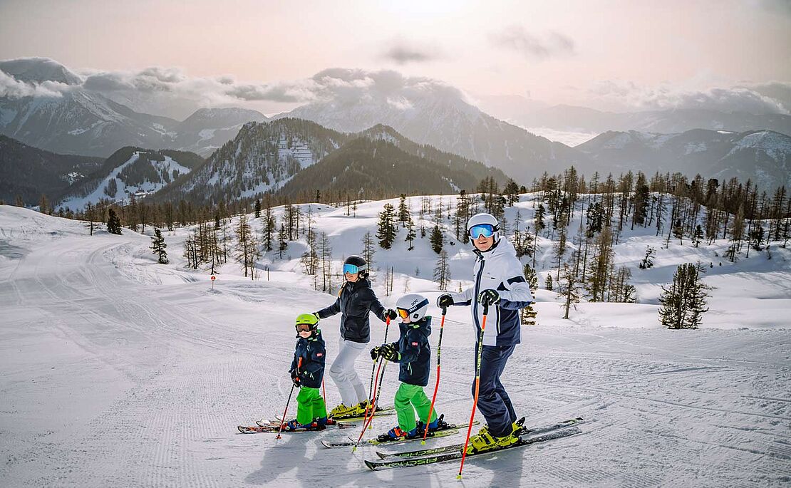 Eine Familie mit zwei Kindern auf Skiern auf Skipiste