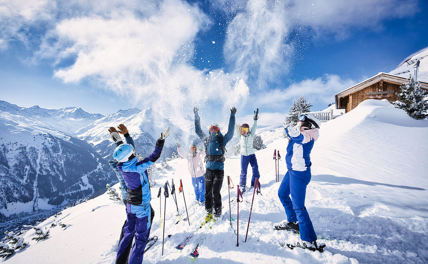 Gruppe von Skifahrern strecken auf einer Piste in St. Anton am Arlberg die Hände in die Höhe