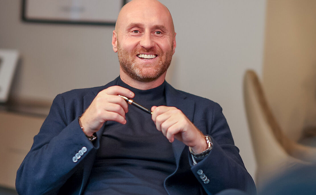 Thomas Hopfgartner sitzend mit Kuli in der Hand