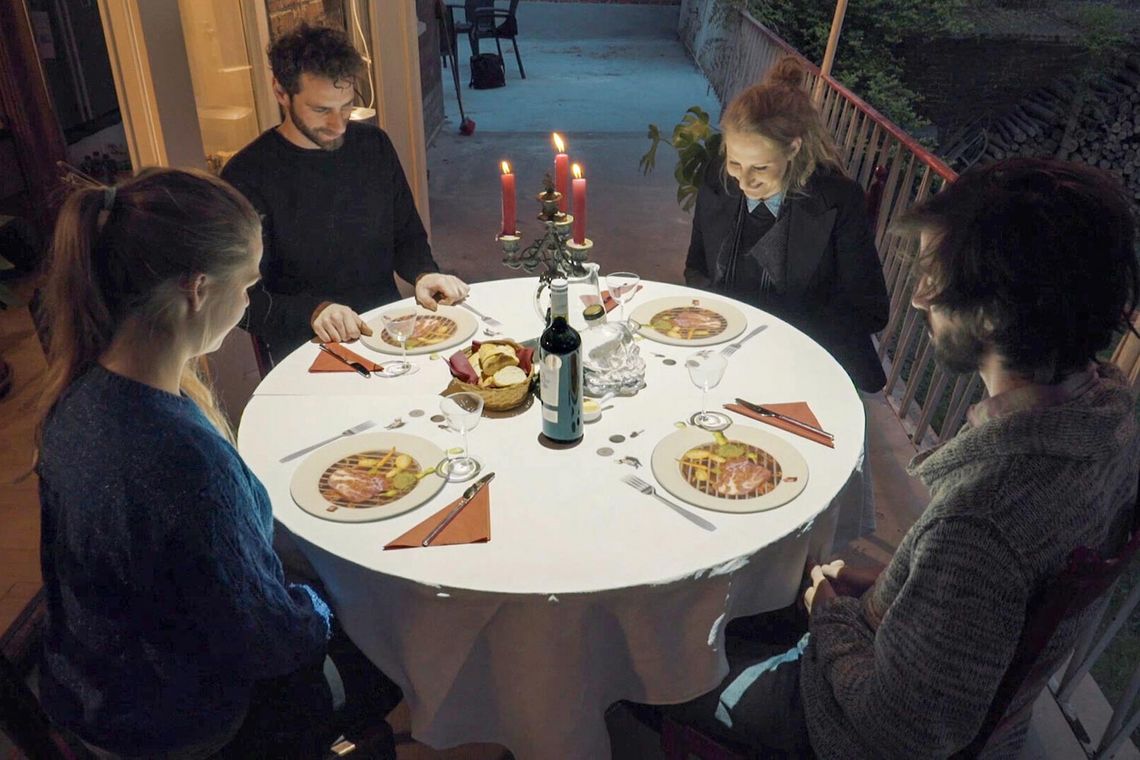 Foto von vier Personen, die an einem runden Tisch sitzen und auf diesen schauen