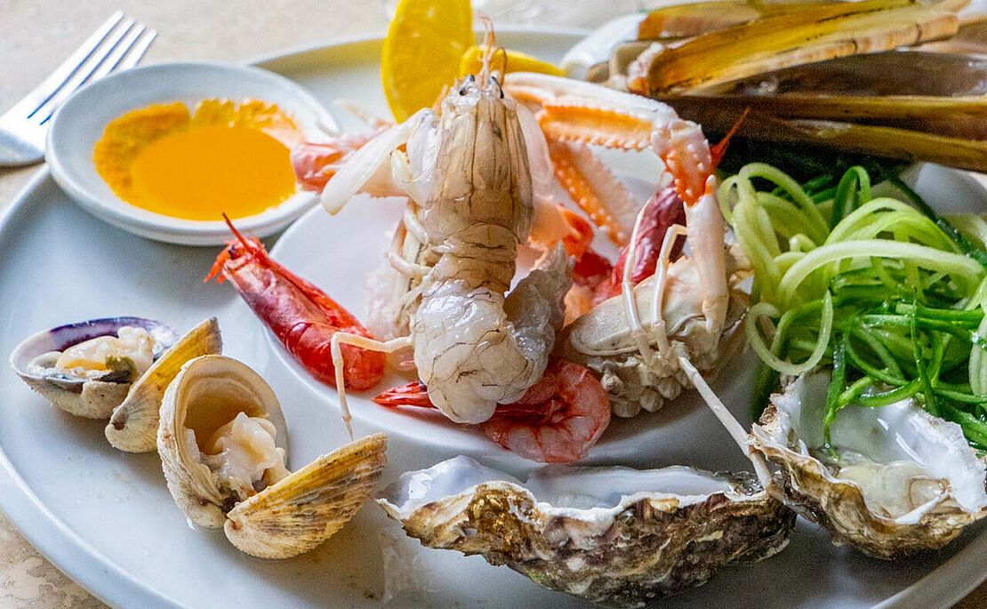 Fischkreation mit Krabbe und Muscheln auf Teller