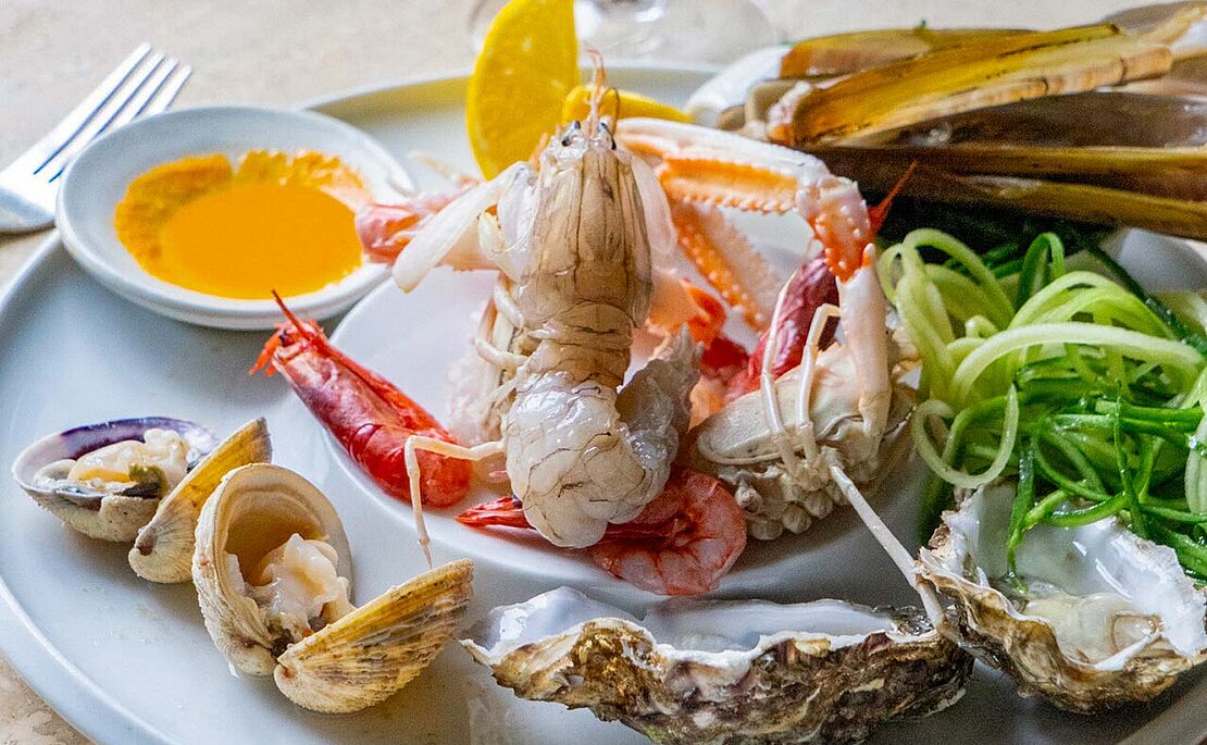 Fischkreation mit Krabbe und Muscheln auf Teller