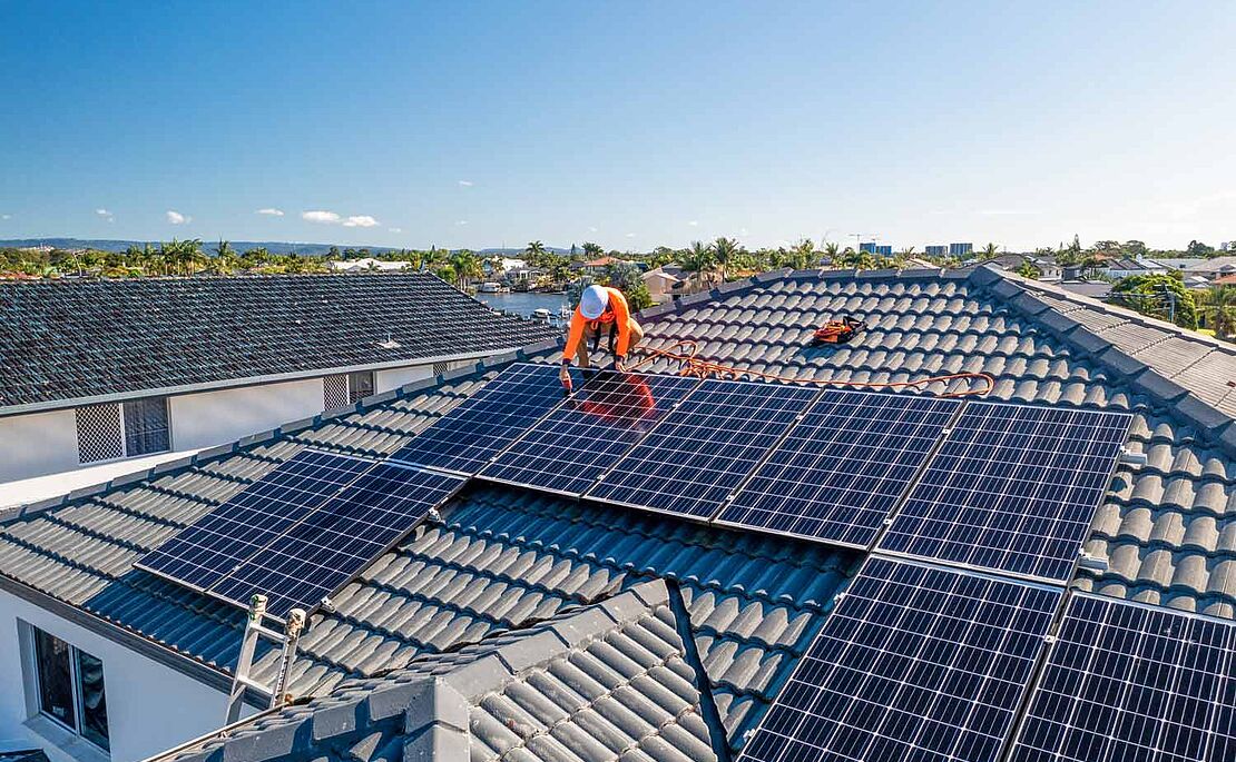 Mann am Dach, der Photovoltaikanlage montiert