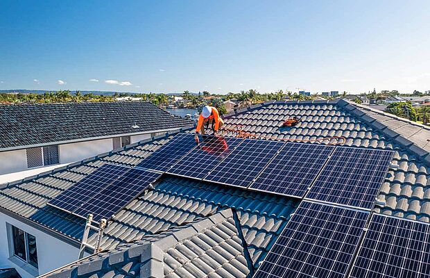 Mann am Dach, der Photovoltaikanlage montiert