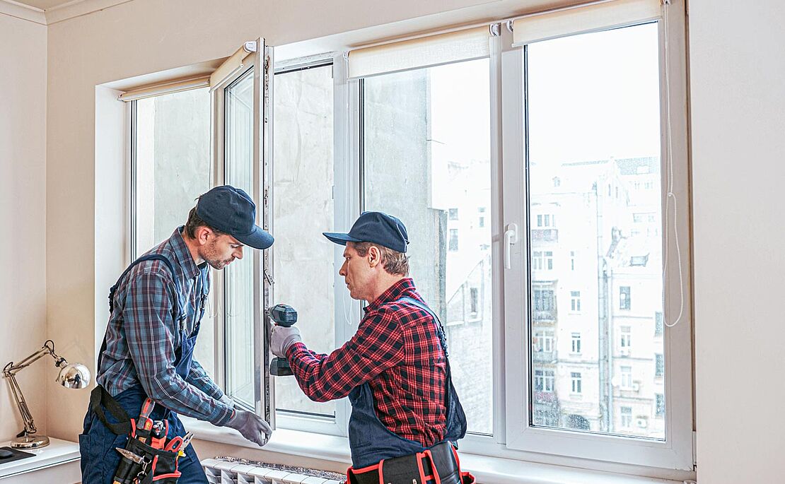 Zwei Handwerker reparieren und schleifen Fensterflügel