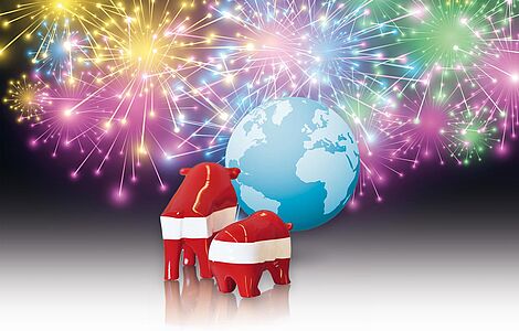 Bulle und Bär in rot-weiß-rot stehen vor einem Global, dahinter Feuerwerk