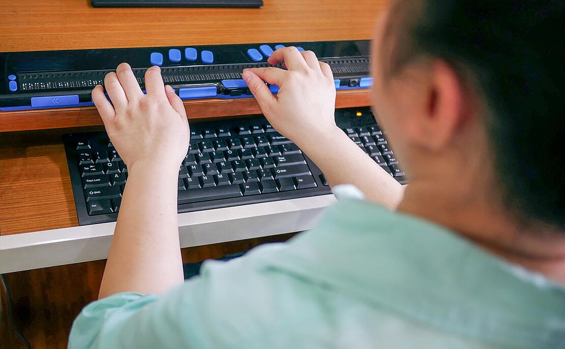 Hände, die auf einer Brailleschrifttastatur liegen