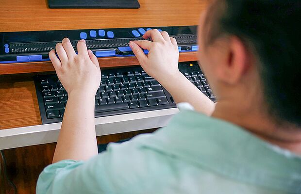 Hände, die auf einer Brailleschrifttastatur liegen