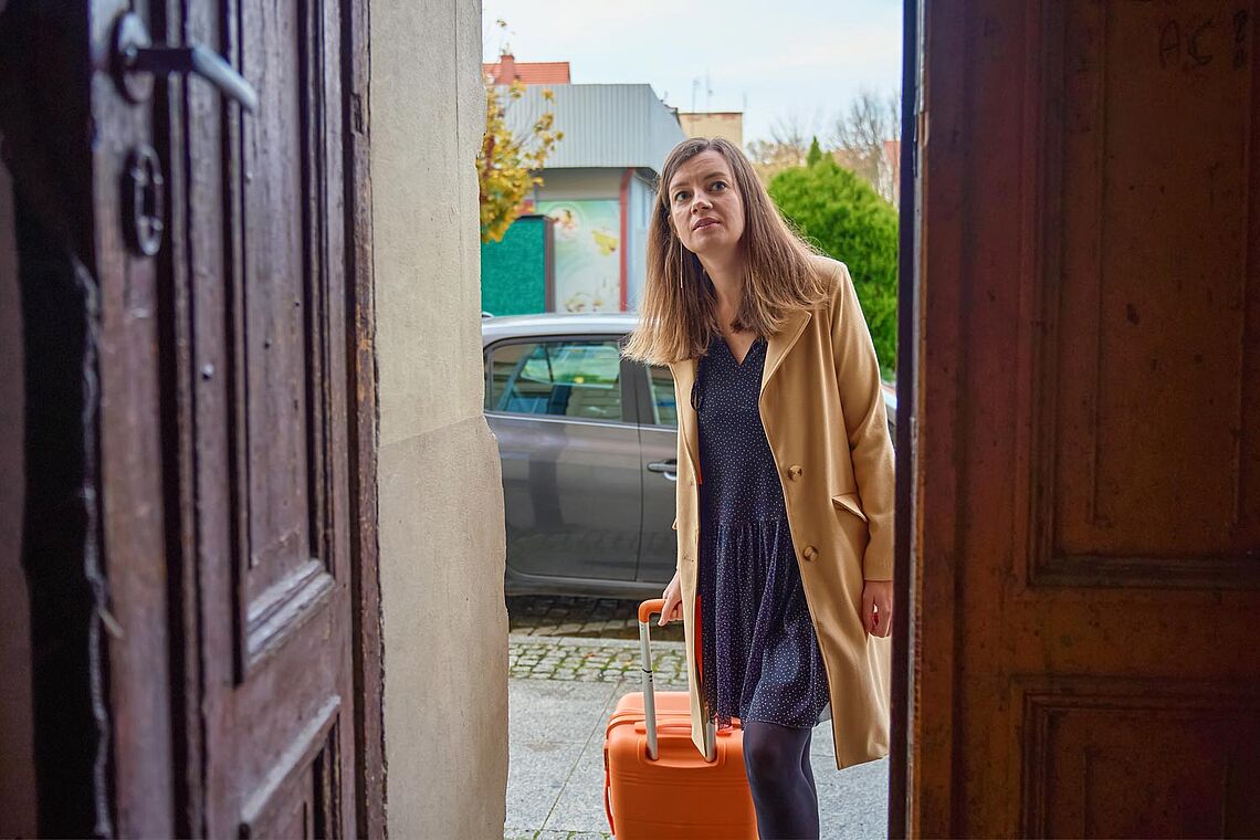 Frau mit Koffer im Hauseingang