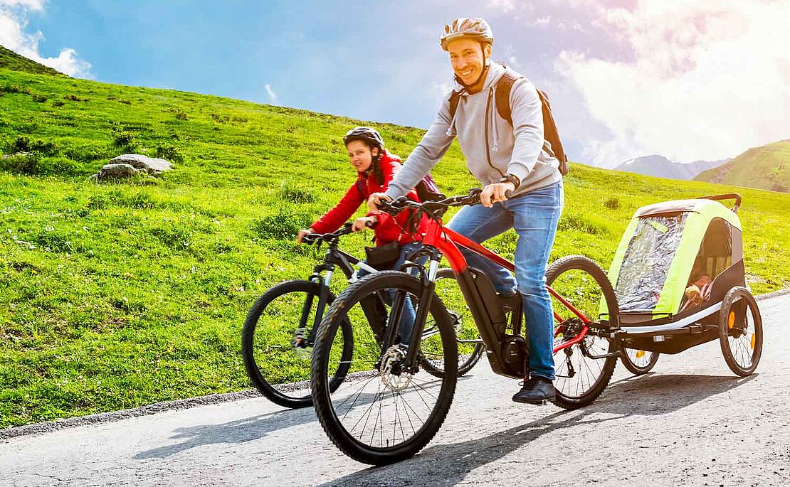 Mann und Mädchen auf einem Fahrrad, Mann mit Anhänger