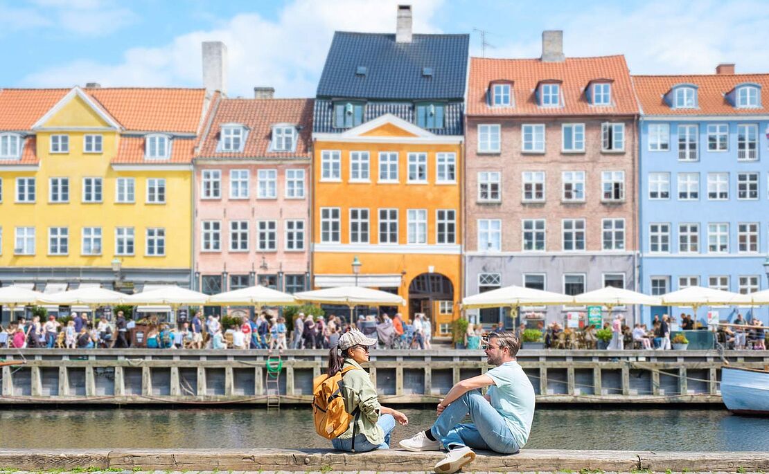 Zwei Menschen sitzen am Hafen in Dänemark