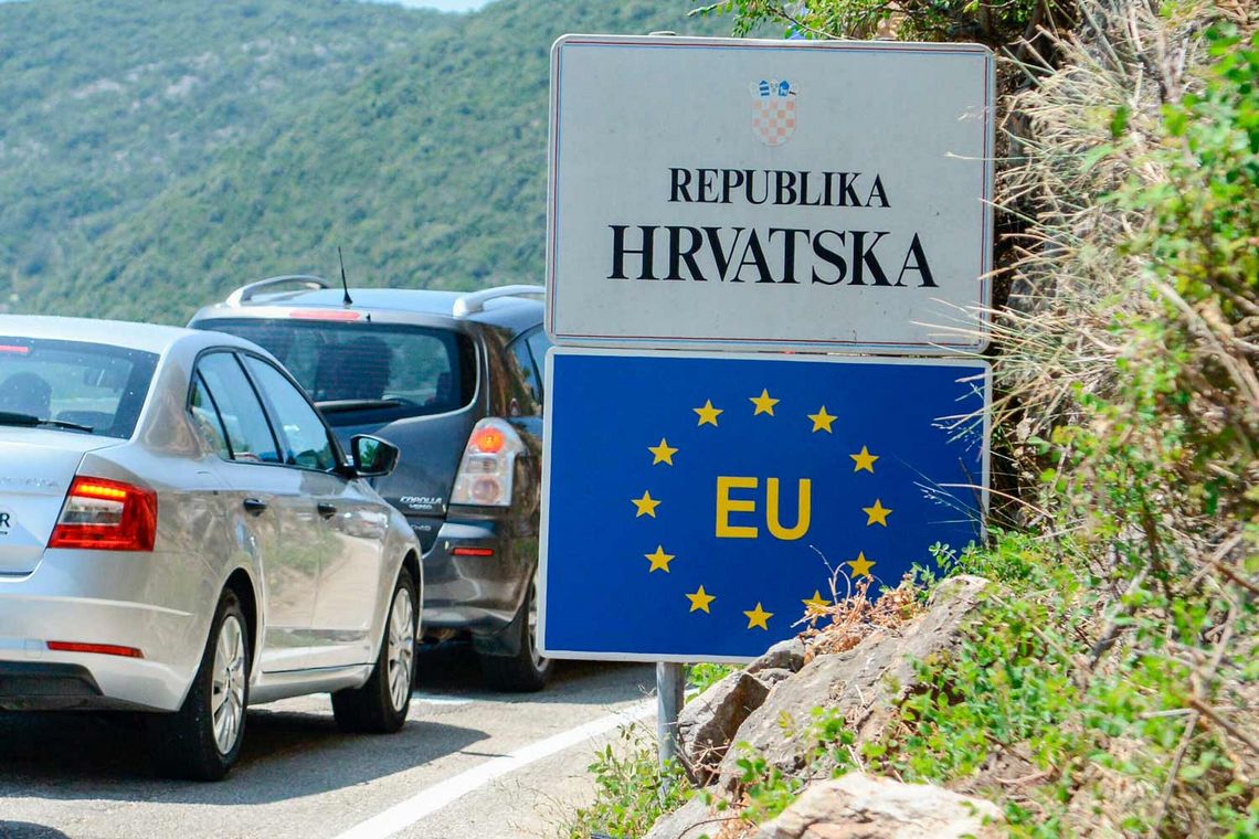 Abbildung von Autos im Stau neben den Schildern  „Republika Hrvatska" und  „EU"