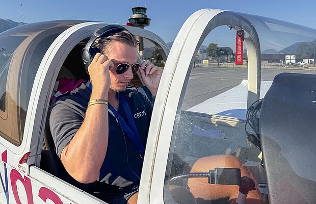 Pilot in einem Cockpit eines Kleinflugzeuges, der sich gerade eine Sonnenbrille aufsetzt