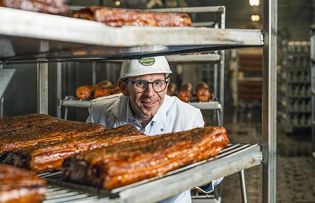 Thomas Schmidbauer schaut durch Regale mit Speck durch