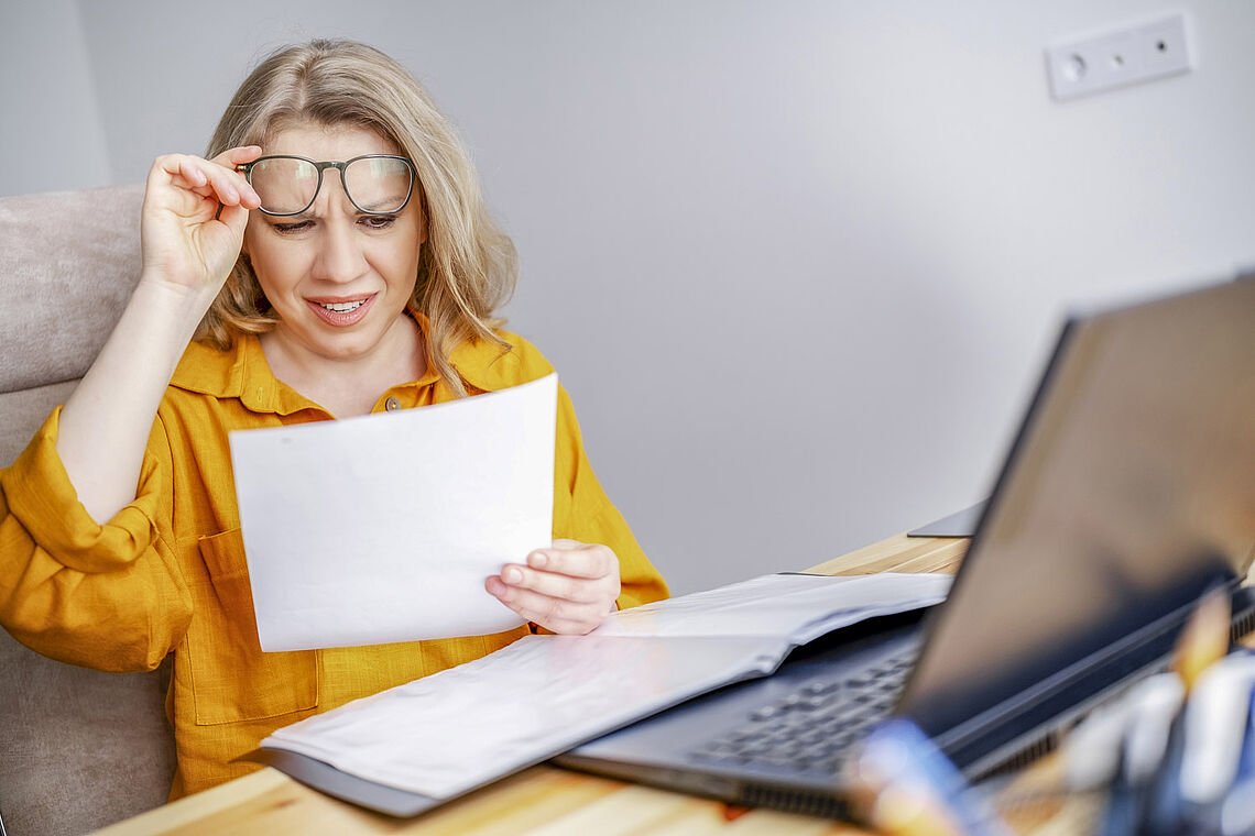 Frau enttäuscht am Schreibtisch lesend
