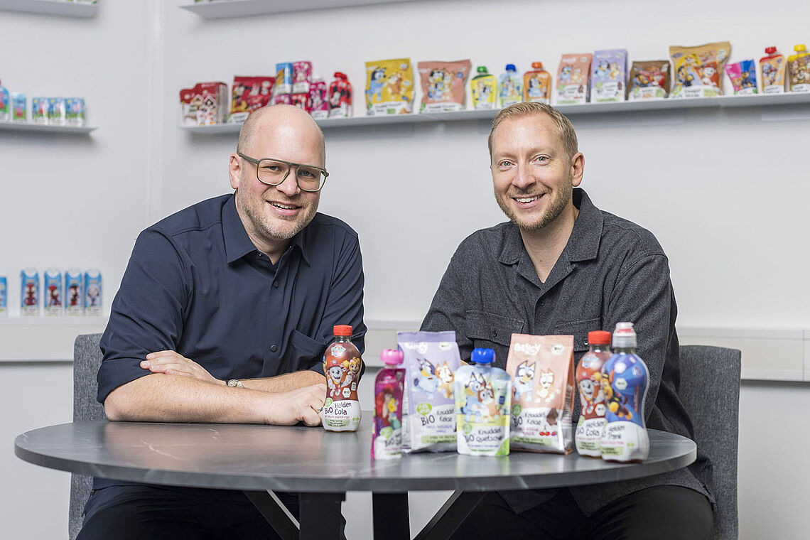 Christian Eibl und Reinhold Hinterplattner bei Tisch sitzend, vor ihnen einige ihrer Produkte