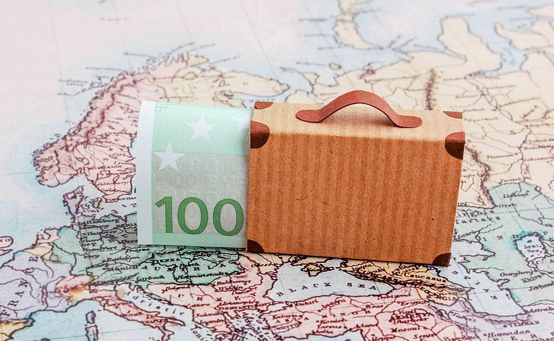 Hundert Euroschein in einem kleinen Köfferchen, auf einer Landkarte platziert