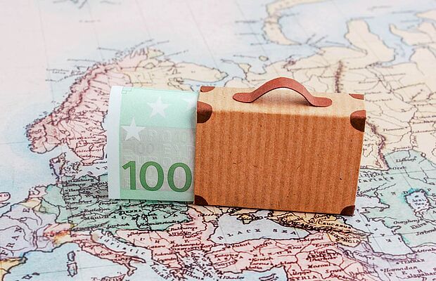 Hundert Euroschein in einem kleinen Köfferchen, auf einer Landkarte platziert