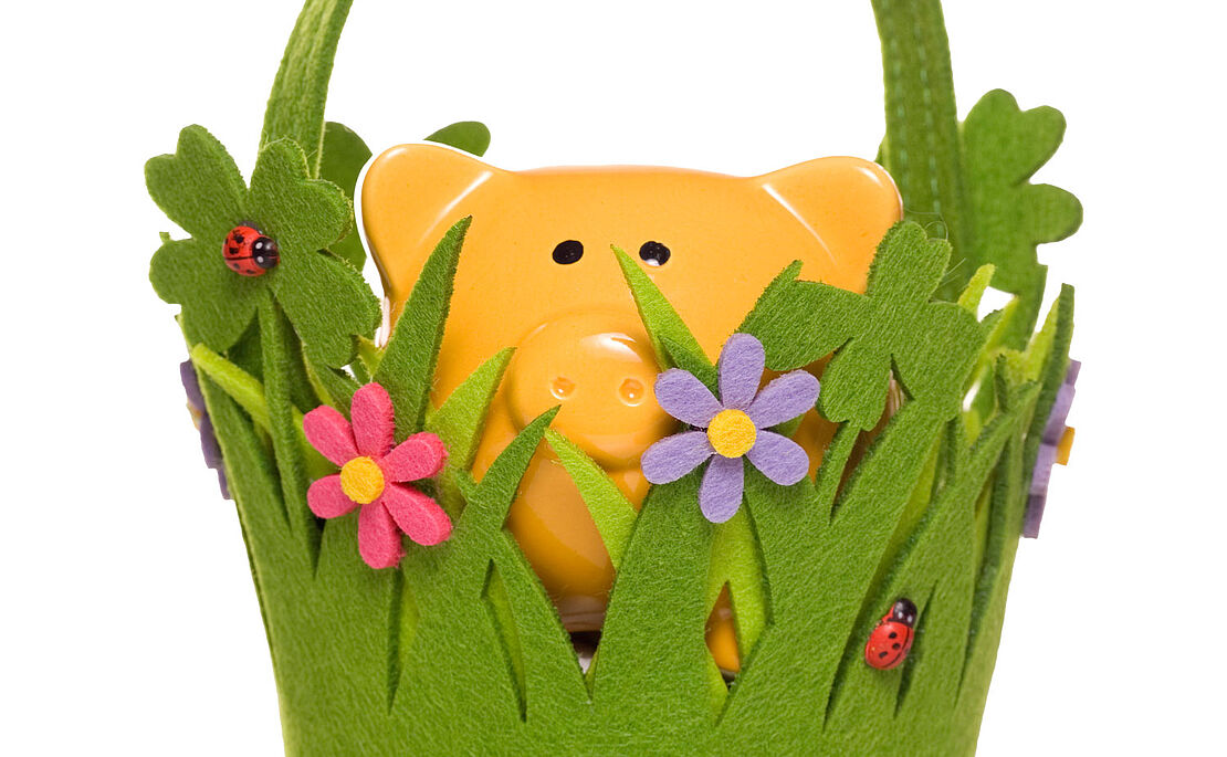 Gelbes Sparschwein in einem Filzkörbchen, das wie eine Wiese aussieht