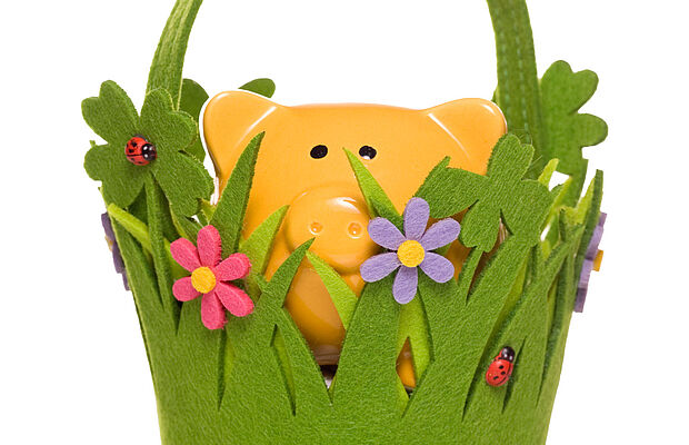 Gelbes Sparschwein in einem Filzkörbchen, das wie eine Wiese aussieht