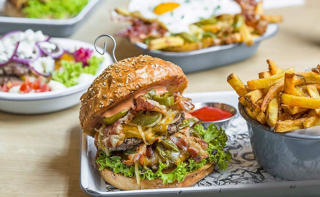 Teller mit einem Burger und einer Schale mit Pommes Frites vom Lokal Omnom