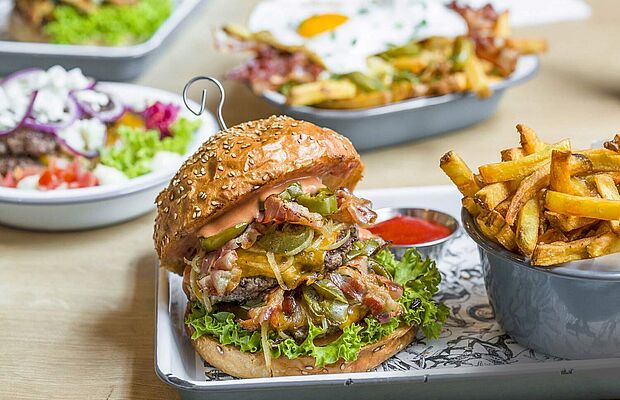 Teller mit einem Burger und einer Schale mit Pommes Frites vom Lokal Omnom